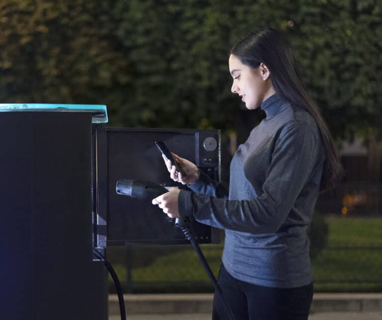 Nainen lataa sähköautoa