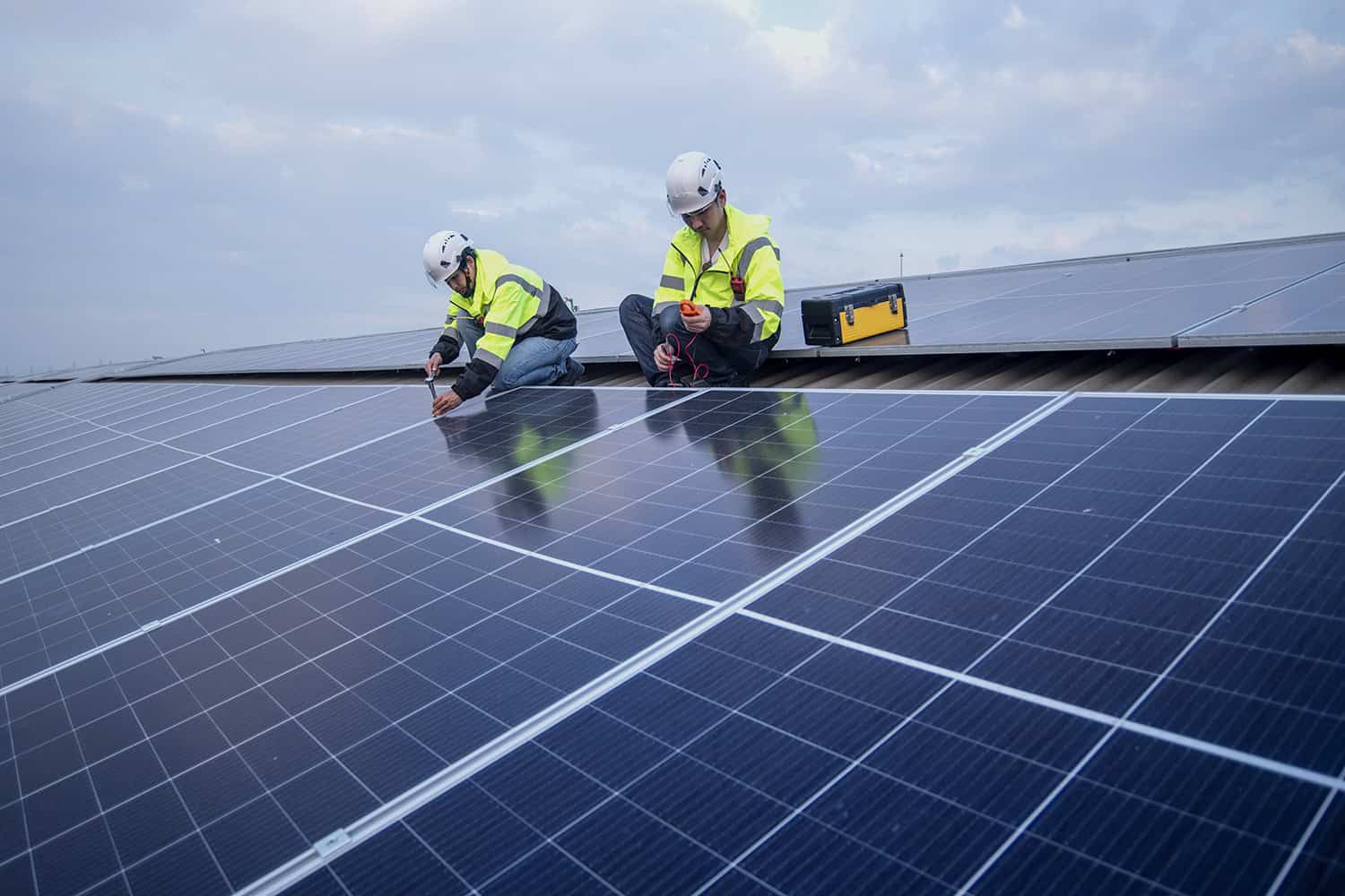 Rakennusmiehet asentavat aurinkopaneeleita